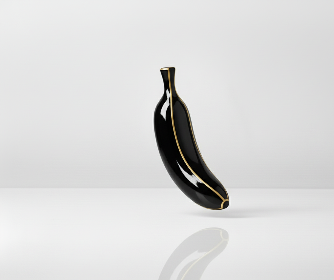 A glossy black banana-shaped sculpture with elegant gold outlining, floating gracefully against a minimalist white background.